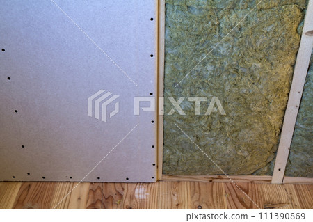 Wooden frame for future walls with drywall plates insulated with rock wool and fiberglass insulation staff for cold barrier. Comfortable warm home, economy, construction and renovation concept. Wooden frame for future walls with drywall plates insulated with rock wool and fiberglass insulation staff for cold barrier. Comfortable warm home, economy, construction and renovation concept. 111390869