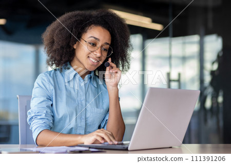 A woman is using a laptop computer on a desk, surrounded by office supplies as a white-collar worker. 111391206