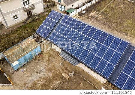 Aerial top view of new modern residential house cottage with blue shiny solar photo voltaic panels system on roof. Renewable ecological green energy production concept. 111391545