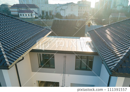 Closeup of house roof top covered with ceramic shingles with gutter pipes for rain water. Tiled covering of building Closeup of house roof top covered with ceramic shingles with gutter pipes for rain water. Tiled covering of building 111391557