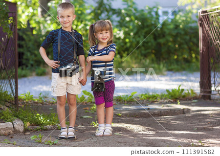 Little boy and a little girl wit two vintage cameras standing together holding hands 111391582