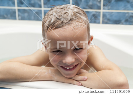 Adorable baby boy with shampoo soap suds on hair taking bath. Closeup portrait of smiling kid, health care and hygiene concept as logo. Isolated on white and blue background with clipping path. Adorable baby boy with shampoo soap suds on hair taking bath. Closeup portrait of smiling kid, health care and hygiene concept as logo. Isolated on white and blue background with clipping path. 111391609