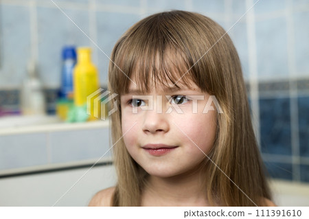 Pretty girl face portrait, smiling child with beautiful eyes and long wet fair hair on blurred background of bathroom. Pretty girl face portrait, smiling child with beautiful eyes and long wet fair hair on blurred background of bathroom. 111391610