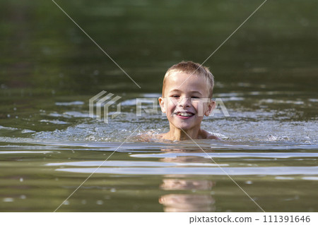 Young smiling child boy swimming in muddy water on sunny summer day. Active lifestyle and safety. Young smiling child boy swimming in muddy water on sunny summer day. Active lifestyle and safety. 111391646