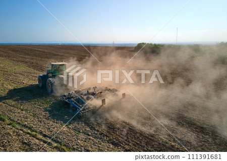 Aerial view of tractor plowing agriculural farm field preparing soil for seeding in summer 111391681