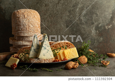 Cheese, bread, walnuts, and thyme on a stone kitchen table. 111392304