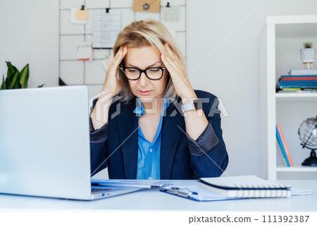 Shocked 50's mature businesswoman, middle-aged experienced female looking at documents in office. Accounting report. Frustrated worried face expression emotion feelings problem perception reaction. Shocked 50's mature businesswoman, middle-aged experienced female looking at documents in office. Accounting report. Frustrated worried face expression emotion feelings problem perception reaction. 111392387