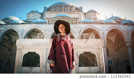 A young girl traveler in a stylish red poncho  111392541