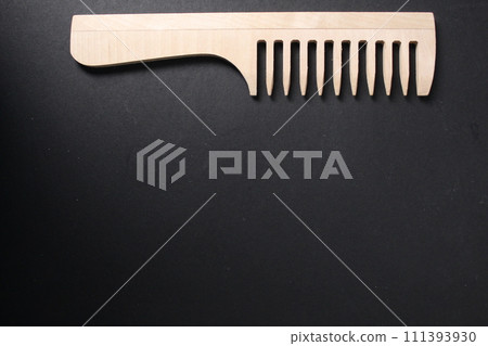 Concept of selection of tools for hair care. Wooden natural comb on black background. Hair Materials, Combs, Hairdresser's Tools 111393930