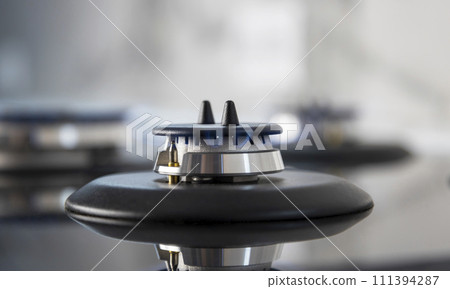 A small gas camphor burns with a blue flame on the kitchen stove. A small gas camphor burns with a blue flame on the kitchen stove. 111394287