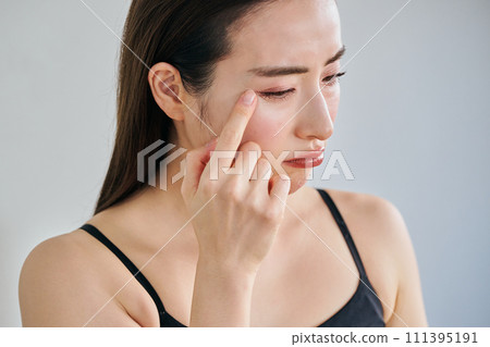 A woman in her 30s worries about wrinkles on her skin while looking in the mirror A woman in her 30s worries about wrinkles on her skin while looking in the mirror 111395191