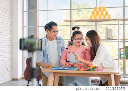 Happy asian father and mother playing education toy with their daughter down syndrome child, As vlogger and live stream online, Activity happy family lifestyle concept. 111395955