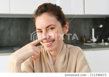 Attractive young cheerful girl baking at the kitchen, making dough, holding recipe book, having ideas 111396673