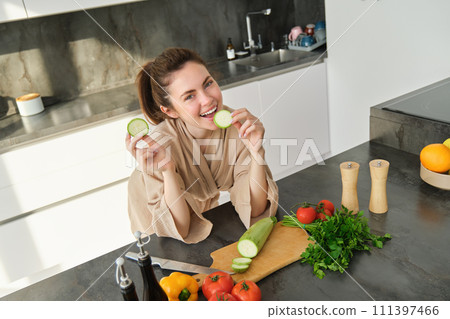 Portrait of good-looking woman cooking salad in the kitchen, chopping vegetables and smiling, preparing healthy meal, leading healthy lifestyle and eating raw food 111397466