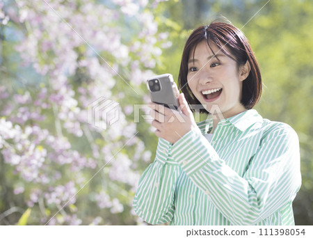 A woman with a smartphone enjoying spring A woman with a smartphone enjoying spring 111398054