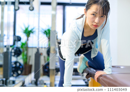 Young woman training her body at a personal gym, one-handed rowing, dumbbell row, muscle training girl Young woman training her body at a personal gym, one-handed rowing, dumbbell row, muscle training girl 111403049