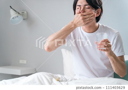 Sick man taking oral medicine, supplements, and pharmaceuticals in the bedroom / Medication Sick man taking oral medicine, supplements, and pharmaceuticals in the bedroom / Medication 111403629