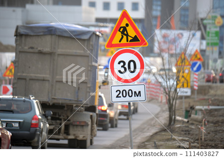 Roadworks warning traffic signs of construction work on city street and slowly moving cars 111403827