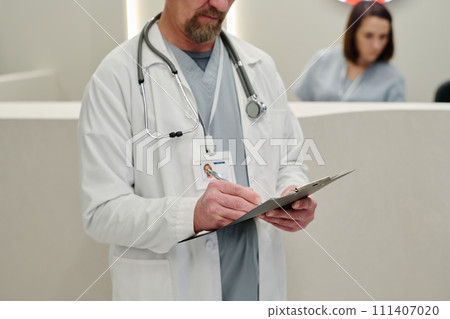 Male clinician making medical notes Male clinician making medical notes 111407020
