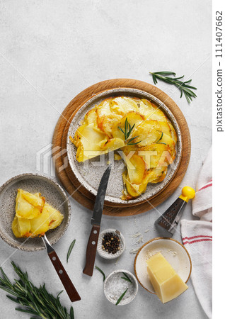Potato gratin - graten with rosemary served on the plate and cutting piece Potato gratin - graten with rosemary served on the plate and cutting piece 111407662