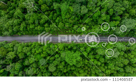 Aerial top view of green electric vehicle car driving over straight forest road, EV car electric vihicle car on forest road with globe green energy and eco power produced from sustainable. Aerial top view of green electric vehicle car driving over straight forest road, EV car electric vihicle car on forest road with globe green energy and eco power produced from sustainable. 111408587