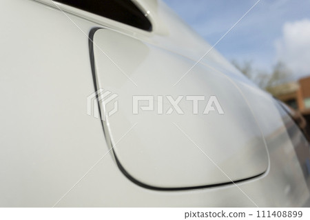 Closeup Scratch On Cap Of Filler Neck, Gas Tank Of White Car. Paint Or Polishing The Clear Coat With A Rubbing Compound. Car Dent Repair. Blue Sky On Background Closeup Scratch On Cap Of Filler Neck, Gas Tank Of White Car. Paint Or Polishing The Clear Coat With A Rubbing Compound. Car Dent Repair. Blue Sky On Background 111408899