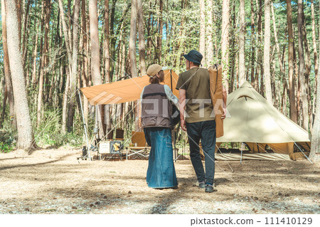 Asian couple campers carrying sleeping bags and luggage at the campsite (glamping/forest site) Asian couple campers carrying sleeping bags and luggage at the campsite (glamping/forest site) 111410129
