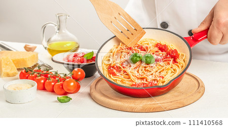 Italian pasta with tomatoes and basil in pan. Chef cooking spaghetti 111410568