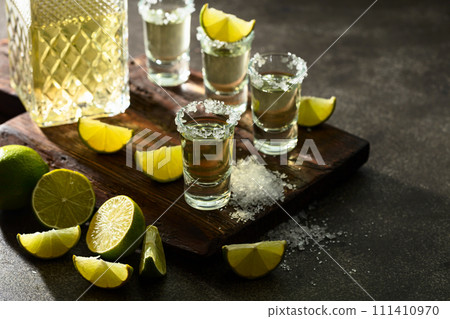 Tequila with sea salt and lime slices on a old cutting board. 111410970