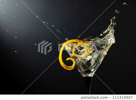 Glass of classic dry martini cocktail with green olives on a black background. Glass of classic dry martini cocktail with green olives on a black background. 111410987