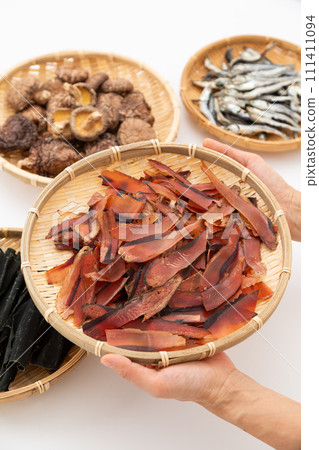 一個女人的手拿著昆布根、乾沙丁魚、乾香菇和厚厚的鰹魚片 一個女人的手拿著昆布根、乾沙丁魚、乾香菇和厚厚的鰹魚片 111411094