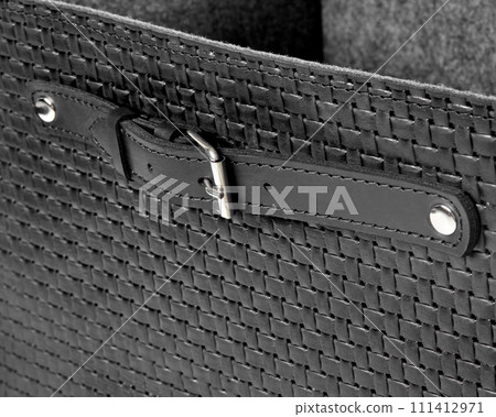 Closeup of black leather woven box with strap handle on rivets with buckle Closeup of black leather woven box with strap handle on rivets with buckle 111412971