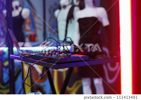 Dj music mixer equipment live concert and discotheque at nightclub stage. Musician controller for sound and volume mixing and headset for live performance in club with spotlight glow close up 111413491
