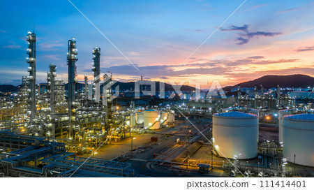 Aerial view oil and gas tank with oil refinery background at night, Glitter lighting of petrochemical plant with night, Manufacturing of petroleum, Products tank in petrochemical plant. Aerial view oil and gas tank with oil refinery background at night, Glitter lighting of petrochemical plant with night, Manufacturing of petroleum, Products tank in petrochemical plant. 111414401