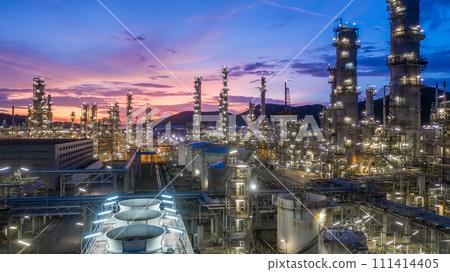 Aerial view oil and gas tank with oil refinery background at night, Glitter lighting of petrochemical plant with night, Manufacturing of petroleum, Products tank in petrochemical plant. Aerial view oil and gas tank with oil refinery background at night, Glitter lighting of petrochemical plant with night, Manufacturing of petroleum, Products tank in petrochemical plant. 111414405