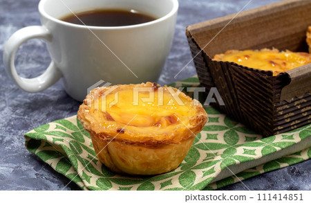 Lots of desserts Pastel de nata or Portuguese egg tart with a white cup of black coffee. Pastel de Belm is a small pie with a crispy puff pastry crust and a custard cream filling 111414851