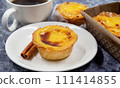 Lots of desserts Pastel de nata or Portuguese egg tart and cinnamon sticks with a cup of coffee. Pastel de Belm is a small pie with a crispy puff pastry crust and a custard cream filling 111414855