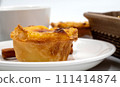 One Pastel de nata or Portuguese egg tart on a white plate. Pastel de Belm is a small pie with a crispy puff pastry crust and a custard cream filling 111414874