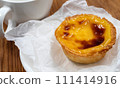 One Pastel de nata or Portuguese egg tart on a white plate. Pastel de Belm is a small pie with a crispy puff pastry crust and a custard cream filling 111414916