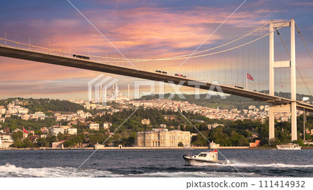 Sailboat traverses the Bosphorus Strait beneath the iconic Bosphorus Bridge, bathed in the warm glow of the setting sun Sailboat traverses the Bosphorus Strait beneath the iconic Bosphorus Bridge, bathed in the warm glow of the setting sun 111414932