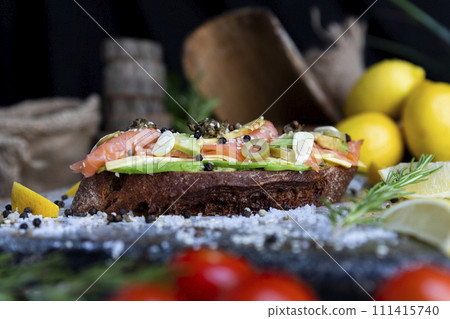 Salted salmon open sandwich with guacamole, avocado, olives, cheese, pesto and garlick. Healthy seafood 111415740