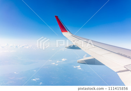View from the airplane window at a beautiful cloudy sky and the airplane wing 111415856