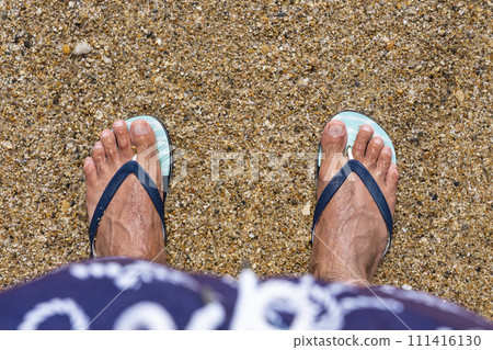 Mans feet in flip-flops at the beach. Top view. Flat lay. Copy space Mans feet in flip-flops at the beach. Top view. Flat lay. Copy space 111416130