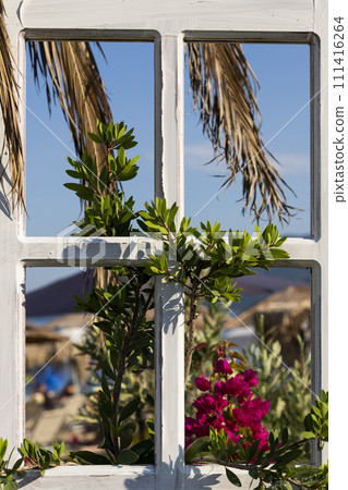 Vintage window frame decorated with flowers and palm tree leaves at the beach Vintage window frame decorated with flowers and palm tree leaves at the beach 111416264