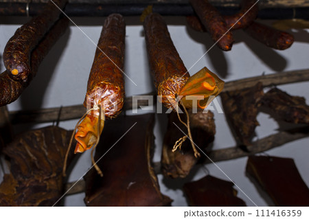 Smoked, dry, cured sausages hanging in an old smokehouse 111416359