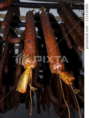 Smoked, dry, cured sausages hanging in an old smokehouse 111416360