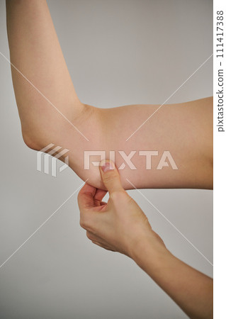A woman in her 30s pinching her upper arm to check for slack. A woman in her 30s pinching her upper arm to check for slack. 111417388
