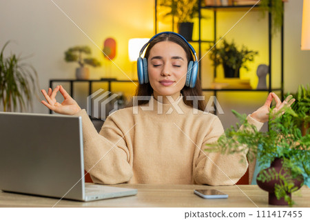 Pretty woman listening music, breathes deeply meditating with concentrated thoughts peaceful at home 111417455