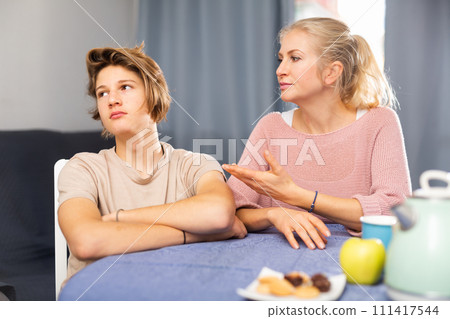 Mother and son sitting after quarrel at home Mother and son sitting after quarrel at home 111417544