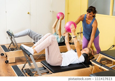 Teenagers training pilates in gym with trainer 111417613